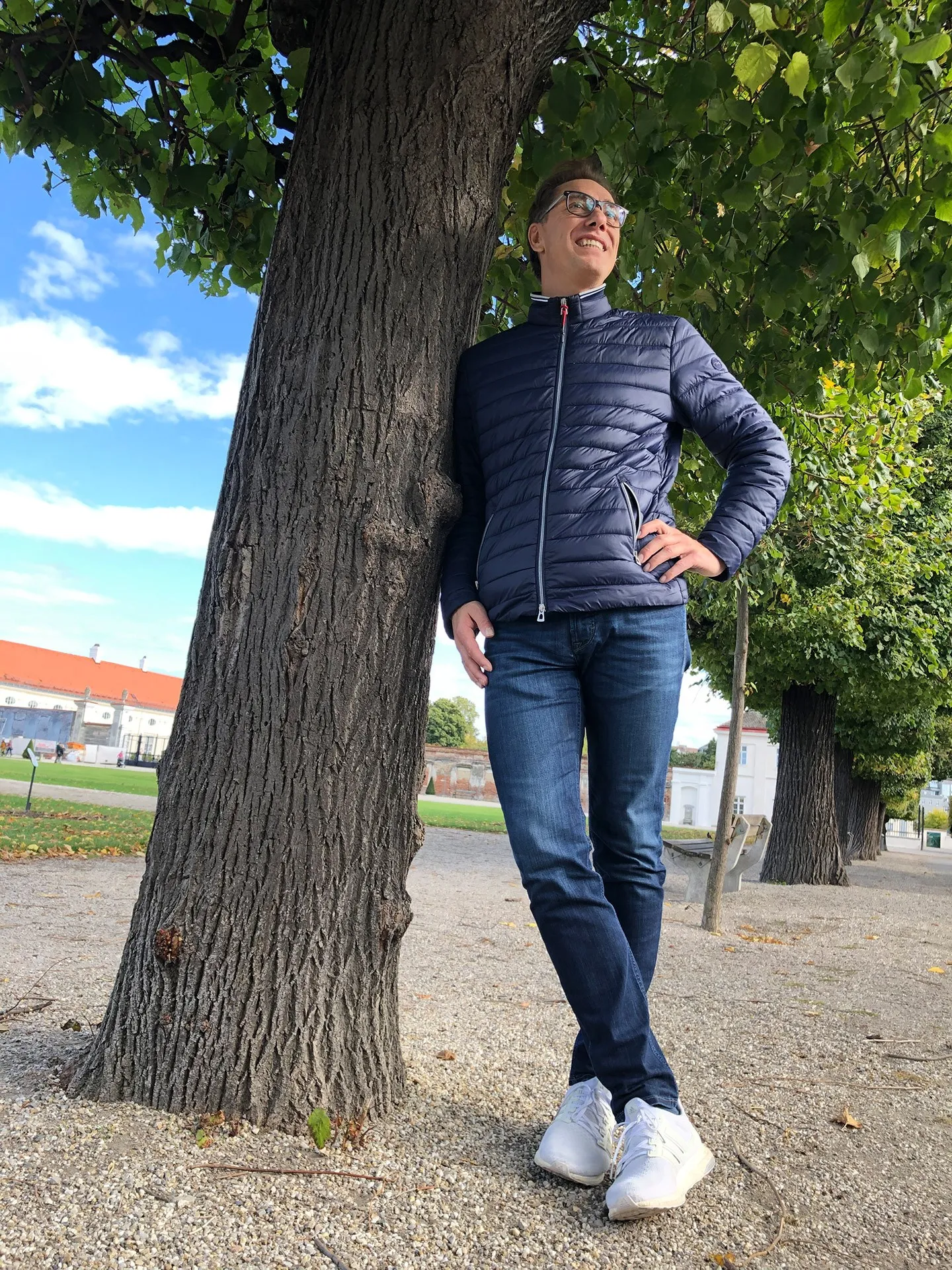 René Müller lehnt in Jeans und Steppjacke an einem Baum